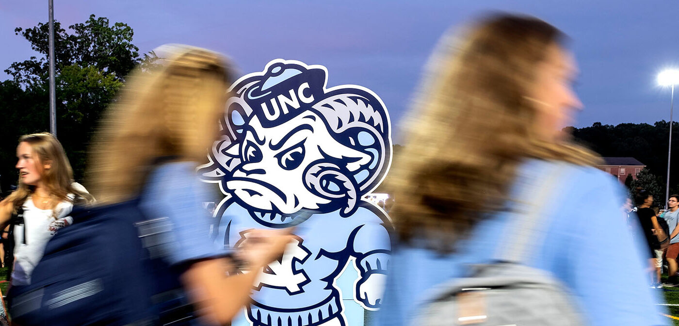 Students pass by a cut out of Rameses in athletic logo form in a blur.