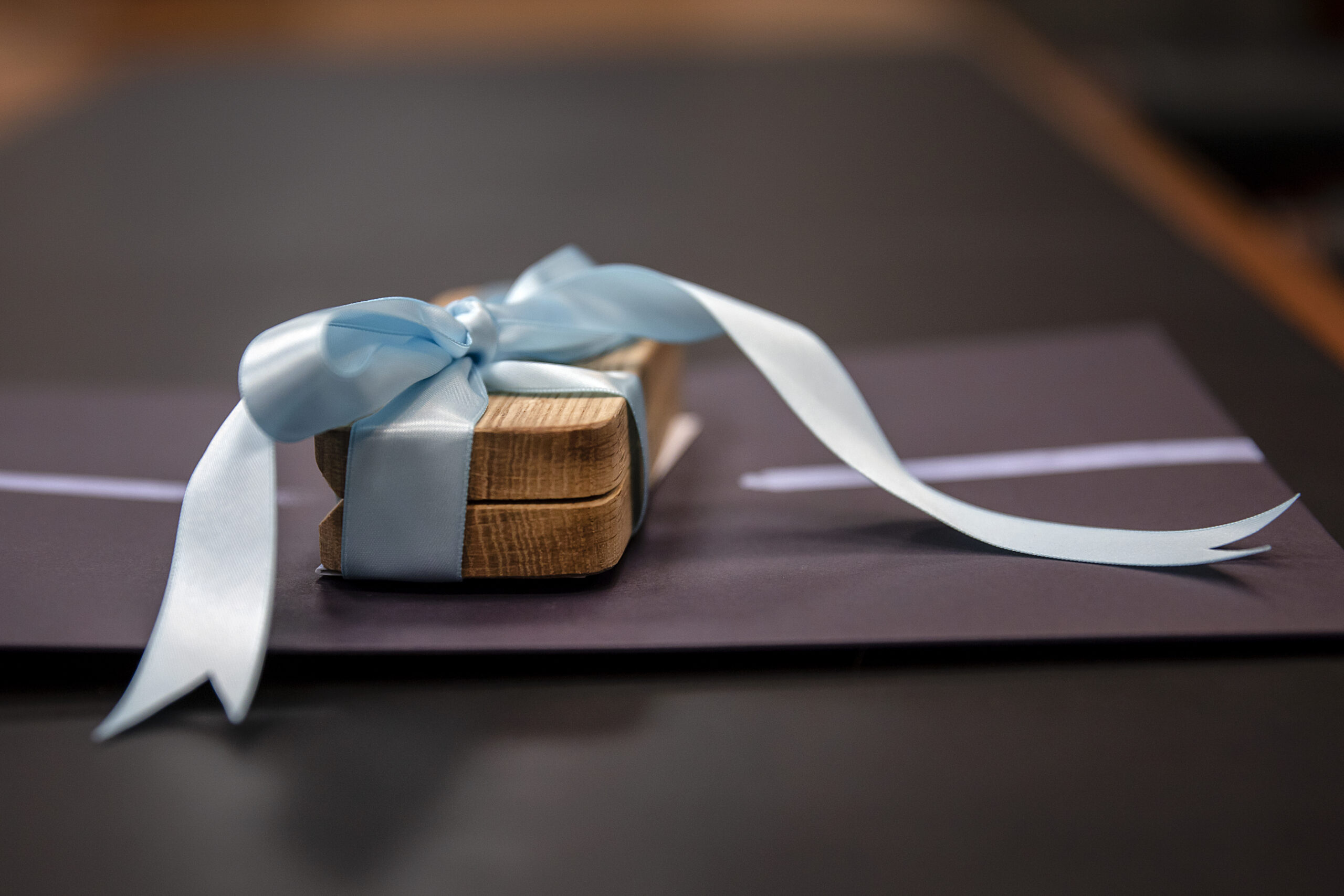 A wooden gift gift with a Carolina blue ribbon sits on a table.
