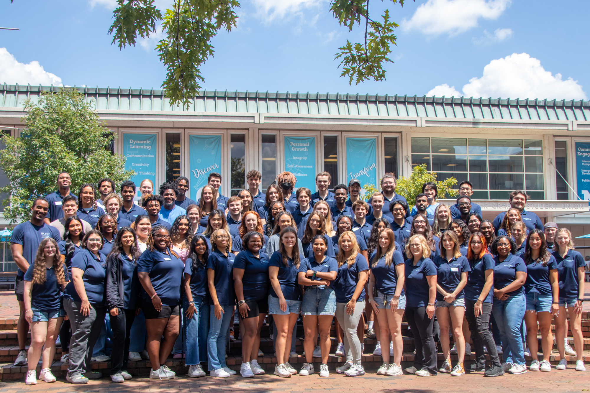 Carolina Union student employees pose for a group photo in the Pit, with the Carolina Union in the background.