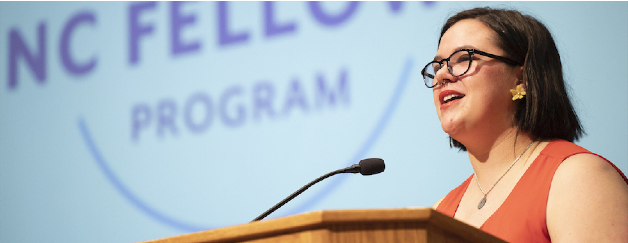 A student speaks on stage at an NC Fellows event.