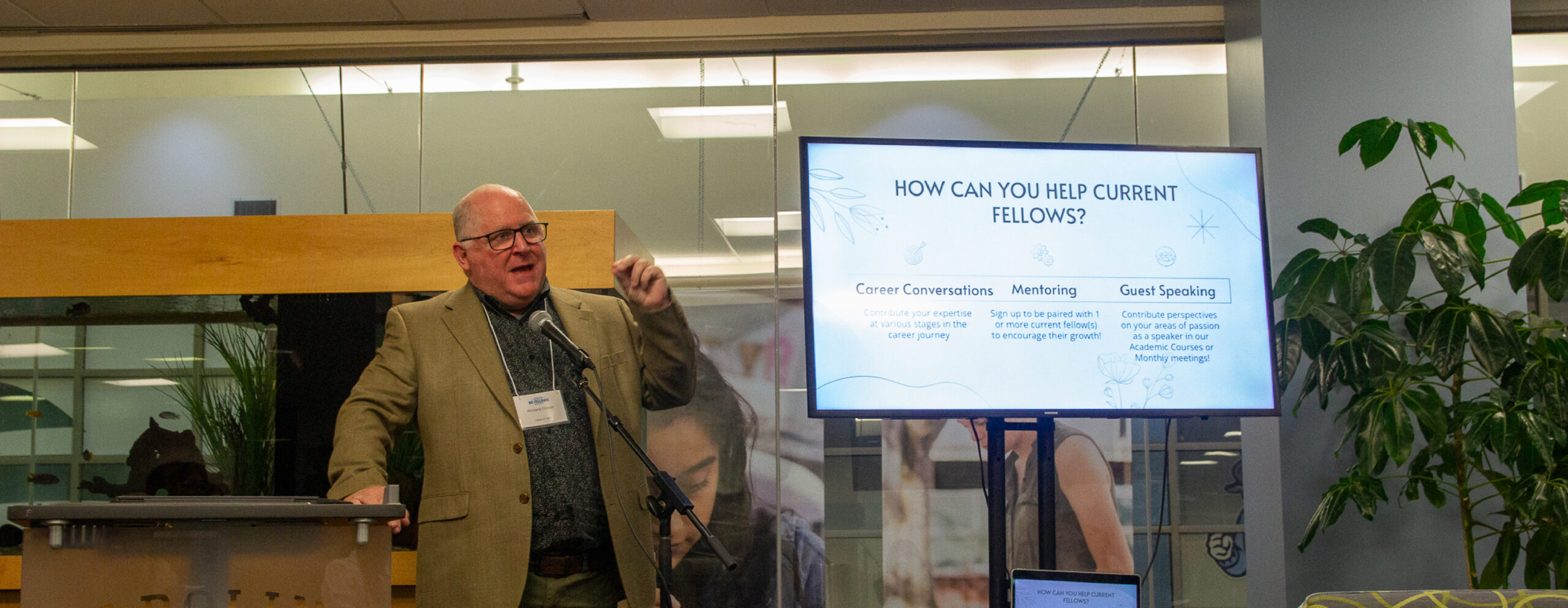 A speaker gives a presentation in front of a projection at the NC Fellows Alumni Homecoming event.