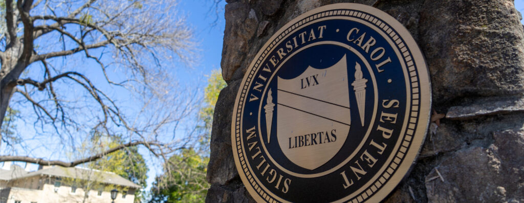 The UNC Chapel Hill seal in gold and black metal on a stone pillar near the heart of campus.