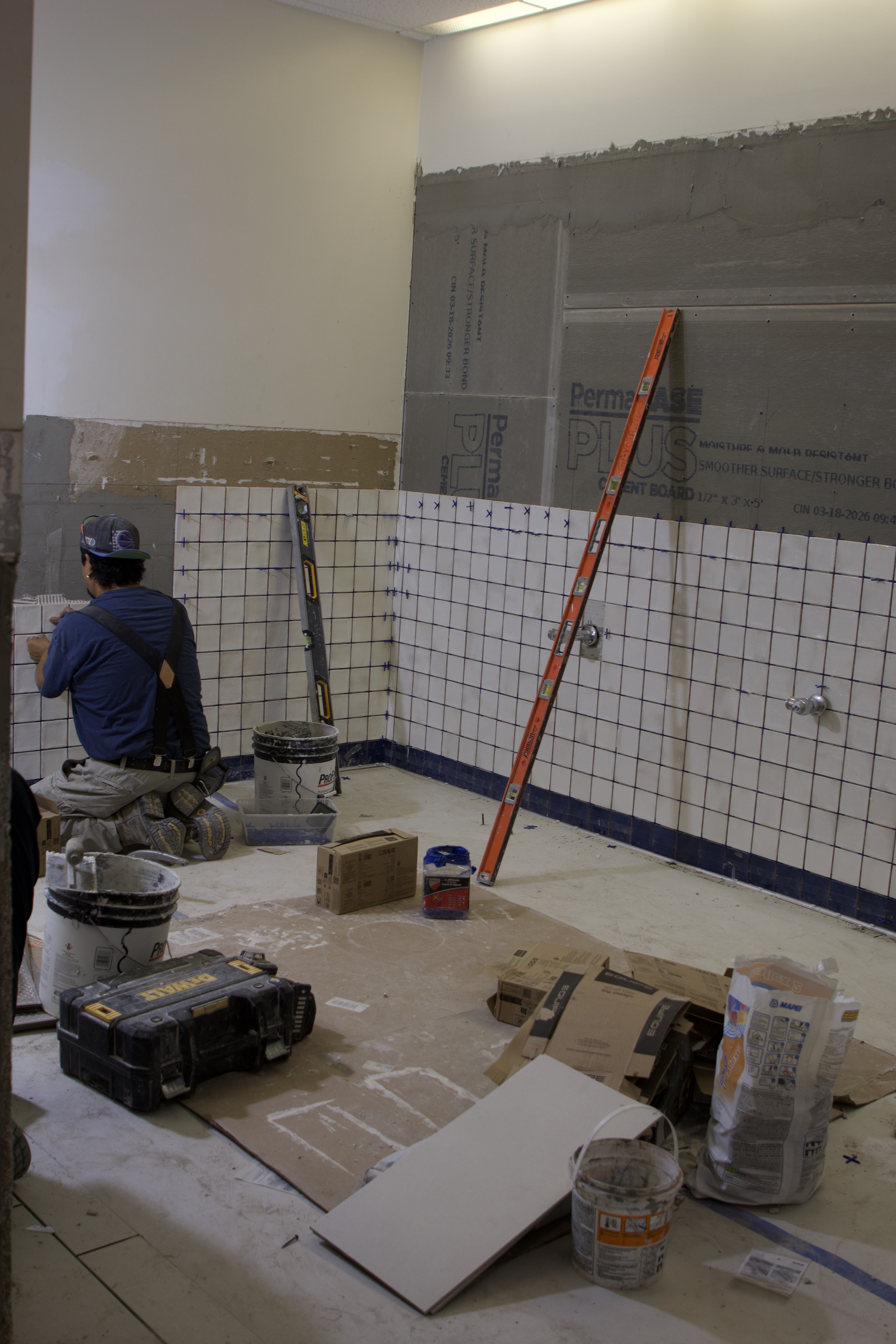 New tile being placed on the walls of the West Lounge bathroom.
