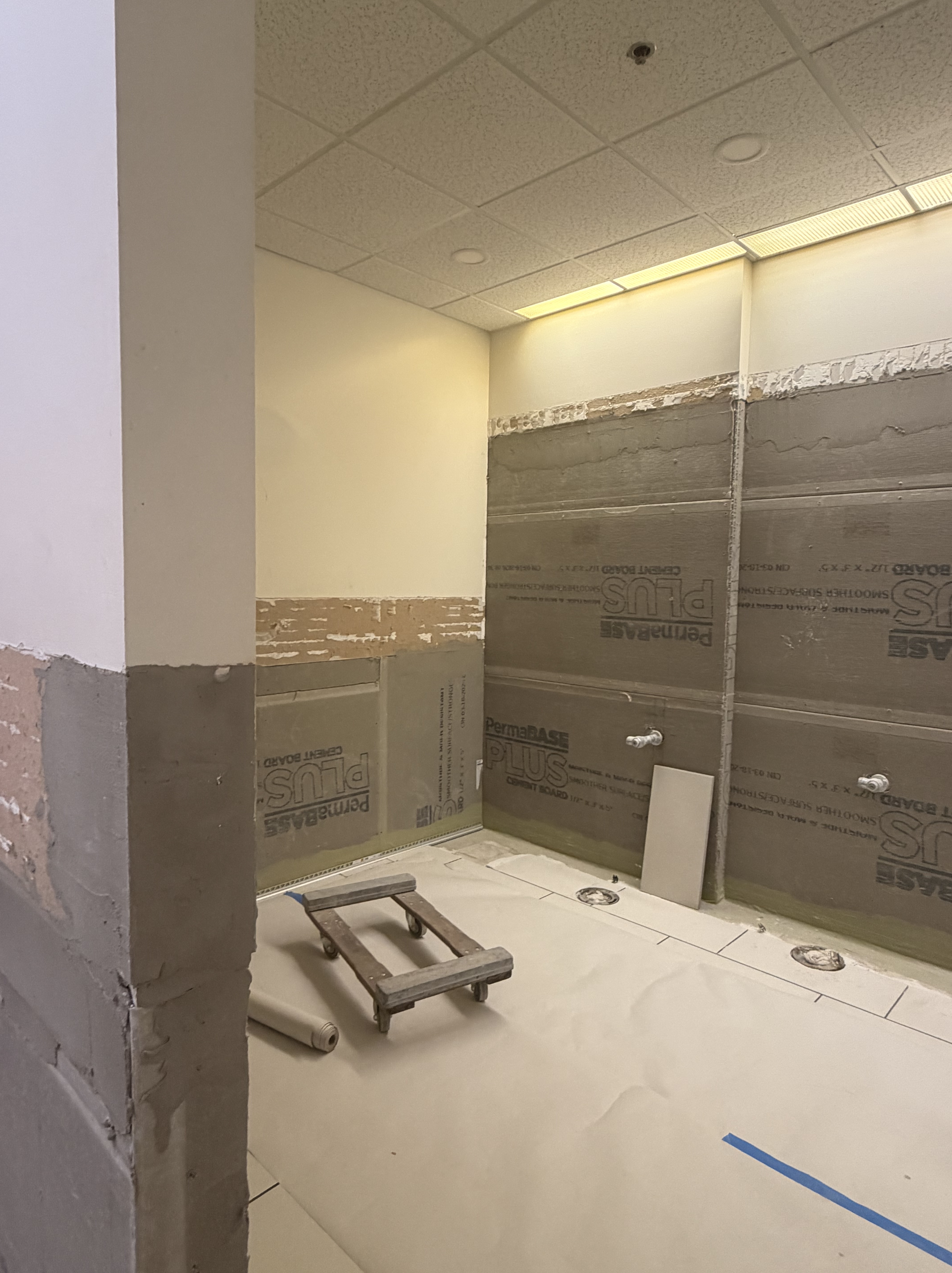 Stripped walls and flooring that are prepared for new tiling in the West Lounge bathrooms.