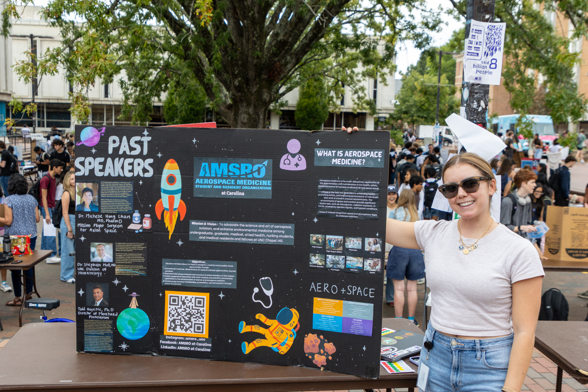 A student wearing sunglasses poses with her poster outside the pit at SOLE Fest 2025.